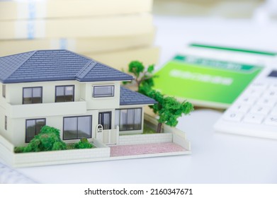 A Model Of A House, A Bunch Of Japanese Yen Bills, And A Japanese Savings Passbook