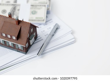 Model house, calculator, cash money and paperwork on a desk: real estate, home loan and investments concept