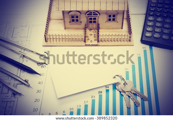 Model house, construction plan for house building,\
keys, blank business card, divider compass. calculator. Real Estate\
Concept. Top view.