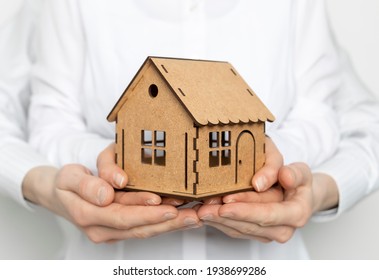 The Model House Is In The Hands Of A Family, A Man And A Woman. Concept For Mortgage Loan Or Real Estate Purchase.