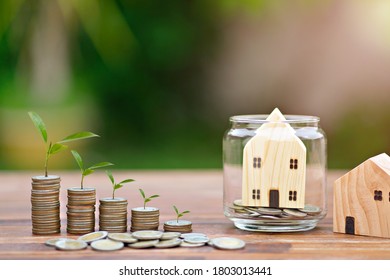 Model of house with money coins stack on wooden table on blurred background. Growing Money - Plant On Coins - Saving And Investment Concept. - Shutterstock ID 1803013441