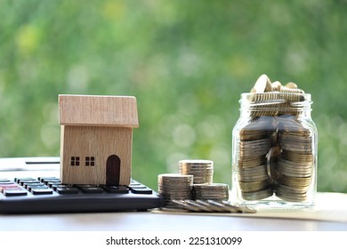 Model house on calculator with stack of coins money in glass bottle on natural green background, Calculating interest payments and Property tax concept  - Shutterstock ID 2251310099