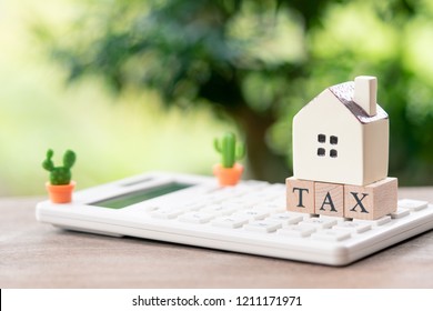 A Model House Model Is Placed On Wood Word TAX . As Background Property Real Estate Concept With Copy Space For Your Text Or  Design.