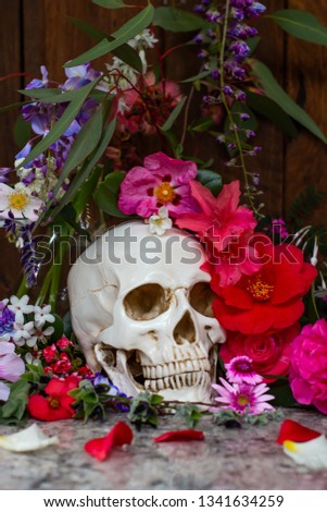 Model of a human skull surrounded by beautiful flowers, concept of death acceptance and loss.
