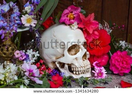 Model of a human skull surrounded by beautiful flowers, concept of death acceptance and loss.