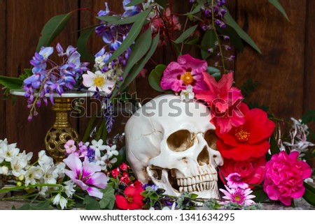 Model of a human skull surrounded by beautiful flowers, concept of death acceptance and loss.