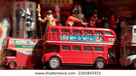 Model of iconic vintage red double decker London bus with slogan 'Best of British' on the side, photographed amongst other toys, figures and models on a shelf in a toy shop in London UK.