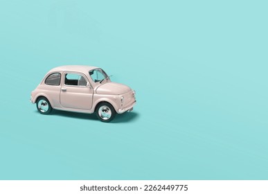 Model pink retro toy car on green background. Miniature car with copy space