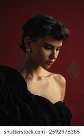 Model poses elegantly with dramatic lighting against a deep red backdrop for a fashion-oriented shoot