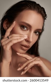 model poses gracefully with subtle makeup, using her hands to frame her face. background is soft, enhancing the focus on her striking features and delicate expression.