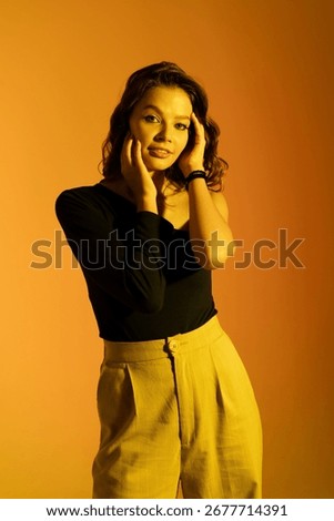 Model posing gracefully against an orange background with defined lighting during a studio photoshoot