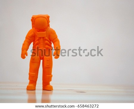 The model printed on a 3d printer. The object in the form of an orange cosmonaut is on the table. Progressive modern additive technology. Copy spase, spase for text.