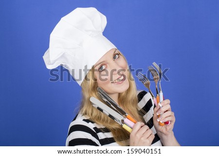 Model Released. Attractive Young Woman in Chefs Hat Holding Kitchen Utensils