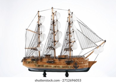 Model ship with sails and rigging displayed on a stand in a simple setting