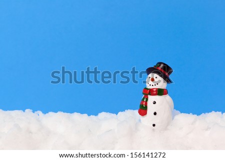 A model snowman on real snow against a plain blue background, add your own text.
