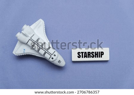 A model space shuttle next to coloured block with text STARSHIP. Emphasizing innovation and the aerospace industry concept  