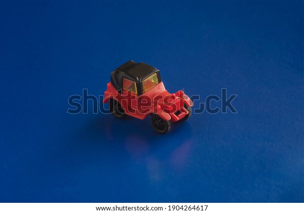 Model of\
a toy retro car on a blue background. Toy red and black car racing\
down the imaginary road. Selective\
Focus.