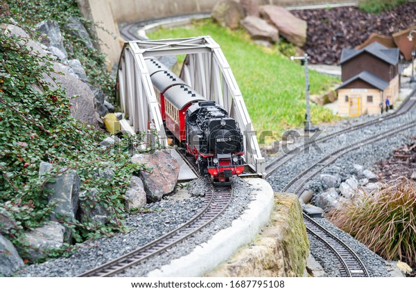 \
A model train that passes\
on a bridge over the tracks in the background is a blurred\
house