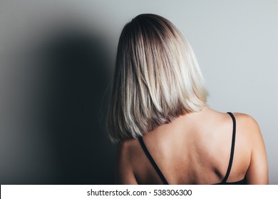 Model with unrecognizable face with blond shiny hair. Woman bob haircut styling. Back view.