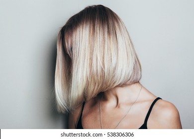 Model with unrecognizable face with blond shiny hair. Woman bob haircut styling.