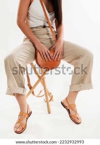 A model wearing a brown sandal shoe and bag in a white background