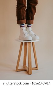 Model In White High Top Sneakers Standing On Chair