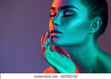 Model woman in colorful bright sparkles and neon lights posing in studio, high fashion portrait of beautiful sexy girl, trendy glowing make-up. Art design colorful and Glittering Vivid neon makeup