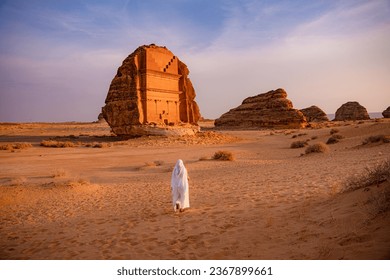 Model woman standing at Hegra preserved tombs set in stunning desert landscape. and learn about the fascinating ancient people and culture of AlUla.