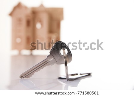 Model of wooden house with house key against white background with copy space. Mortgage, investment real estate or buying a new home concept.