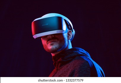 Model young man with beard in glasses of virtual reality on dark background.. Augmented reality, science, future technology concept. VR. Futuristic 3d glasses with virtual projection. Neon light.