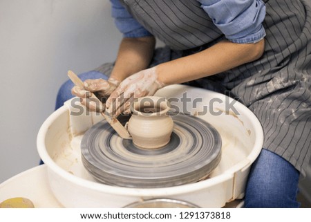 Similar – Young female sitting by table and making clay or ceramic mug