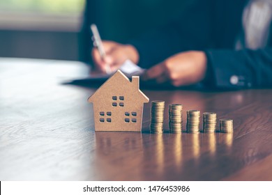 Modeling wooden houses and coins and dollars placed on wooden tables,preparation concept for house model purchase and the fastest growing real estate economy,moving home or renting property via agent - Shutterstock ID 1476453986