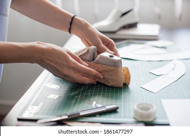 Modelling design of a shoes. Workplace of shoe designer. Hands of designer draw a shoe design on a new shoes at his workshop.
