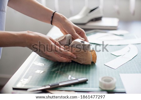 Modelling design of a shoes. Workplace of shoe designer. Hands of designer draw a shoe design on a new shoes at his workshop.