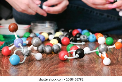Models of molecules from a plastic constructor and peoples hands.