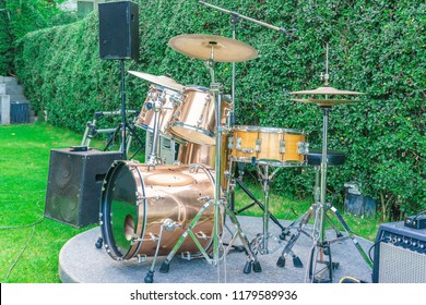 Moderm Drum Set On Stage, Prepared For Playing. Setting Up The Sound System. Concert Is Just About To Begin, Music Event, Performance Outdoors. Green Trees, Leaves In Background