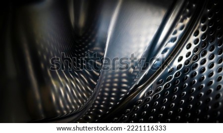 Modern abstract background with shiny metal, distorted black carbon fiber with dark dots, dents, surfaces with angles and curves, closeup view with a copy space.