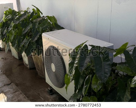Modern AC unit surrounded by lush green foliage in a garden area, energy saving and home cooling concept.
