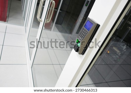 A modern access control system installed at a glass entrance, featuring a keypad and security monitor, enhances the security and technology of office buildings.