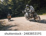 Modern adventure motorcycle on a ride on gravel surface. Motorcycling in nature or offroad, enjoying freedom. Motorbike in the woods. Bike on a bend