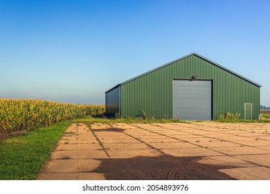 Modern agricultural barn with a yard of concrete slabs. The photo was taken in the Netherlands on a sunny day in the fall season.