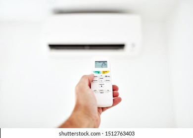 Modern Air Conditioner Unit With A Hand Holding A Remote.