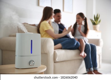 Modern air humidifier and blurred family on background