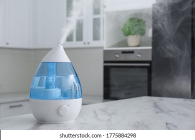 Modern air humidifier on marble table in kitchen. Space for text