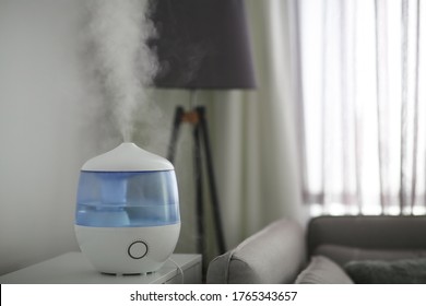 Modern air humidifier on table in living room. Space for text
