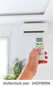 Modern Airconditioner Unit With A Hand Holding A Remote.