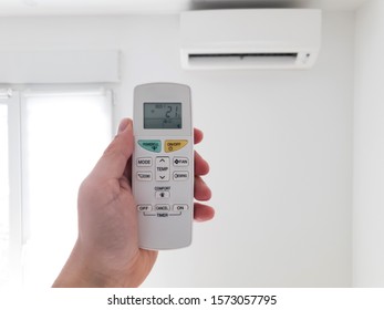 Modern Airconditioner Unit With A Hand Holding A Remote.