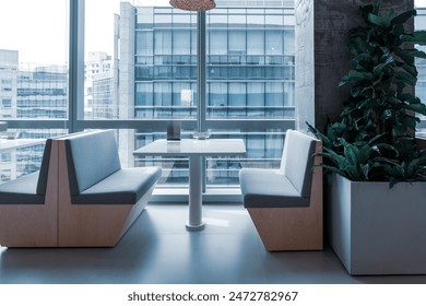 A modern, airy dining or lounge area in an office building. The space features several booth-style seating arrangements with white tables and light gray upholstered seats.  - Powered by Shutterstock