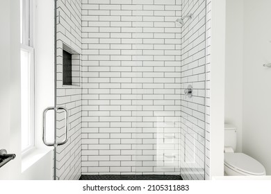 Modern All White Bathroom With White Subway Tile In Shower And Black Hexagon Tile On The Floor