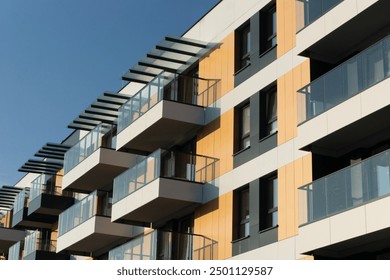 Modern apartment building against a clear blue sky. Residential building architecture. Urban real estate. New build block of flats. Modern living neighbourhood. Sunlight glass balconies. Living area.